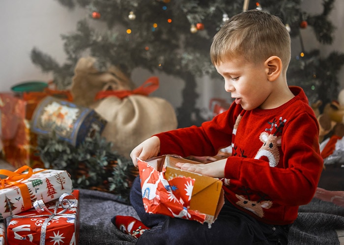 Junge packt Weihnachtsgeschenke aus